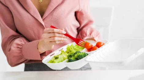cropped view of  woman holding takeaway box with organic vegetables and plastic fork